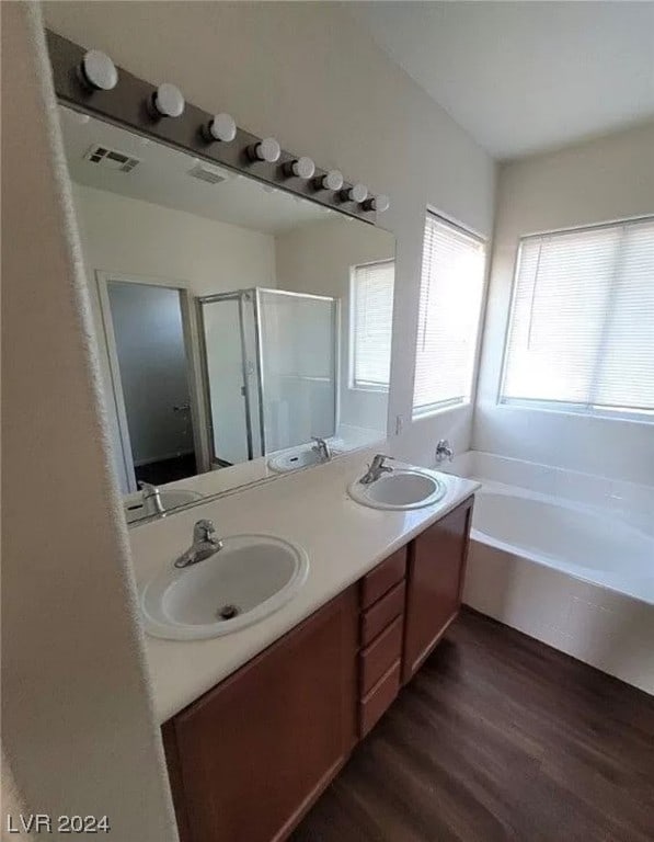 bathroom with double sink, plus walk in shower, large vanity, and wood-type flooring