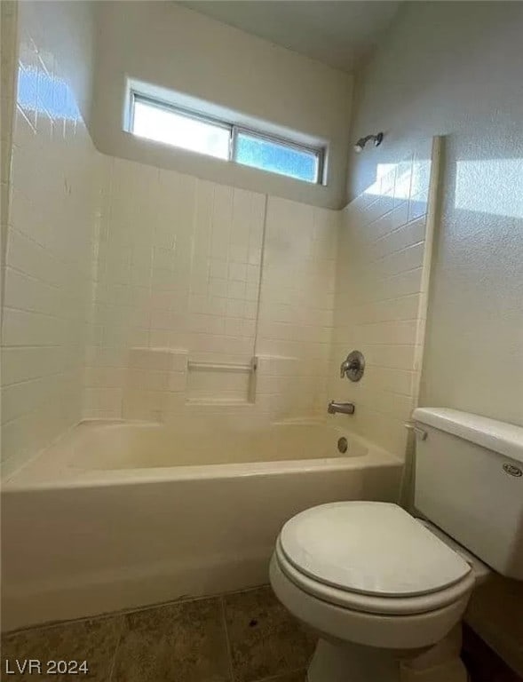 bathroom with tiled shower / bath combo, toilet, and tile floors