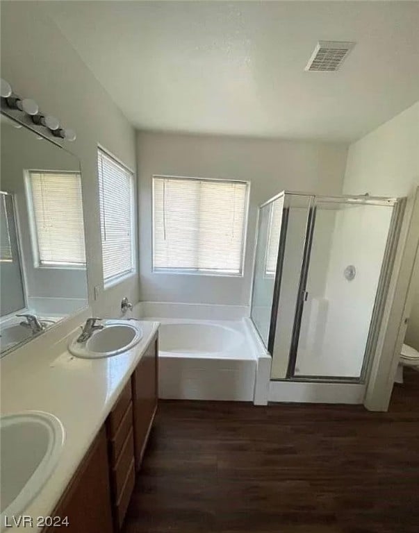 full bathroom featuring toilet, double vanity, plus walk in shower, and hardwood / wood-style flooring