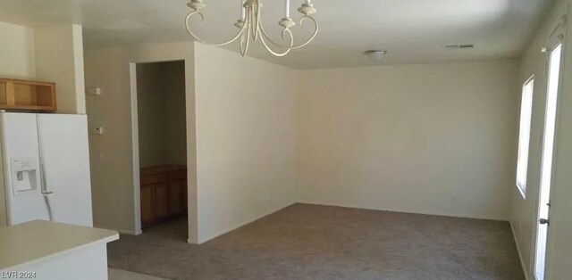 carpeted spare room with a chandelier