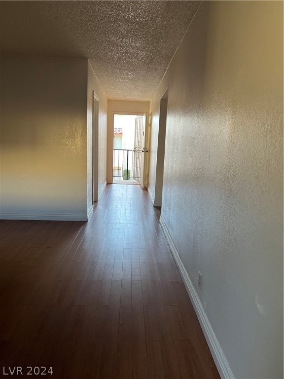 hallway featuring a textured ceiling and dark hardwood / wood-style flooring