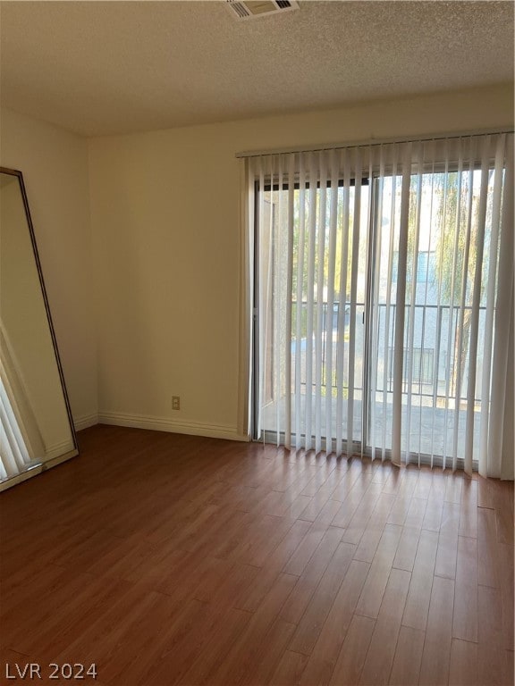 unfurnished room with a textured ceiling and dark hardwood / wood-style floors