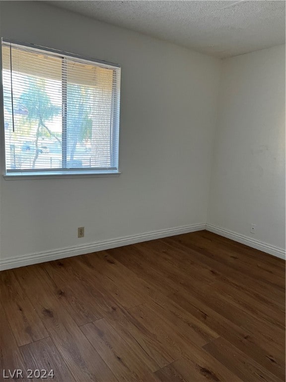 spare room with dark wood-type flooring and a textured ceiling