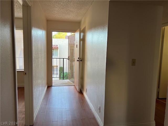 hallway with a textured ceiling and hardwood / wood-style floors