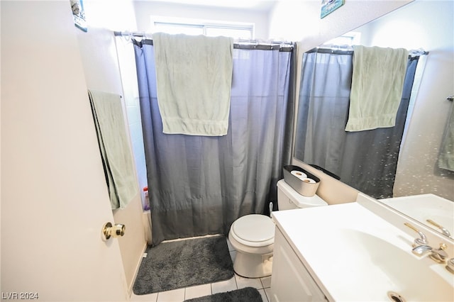 bathroom with toilet, large vanity, and tile floors