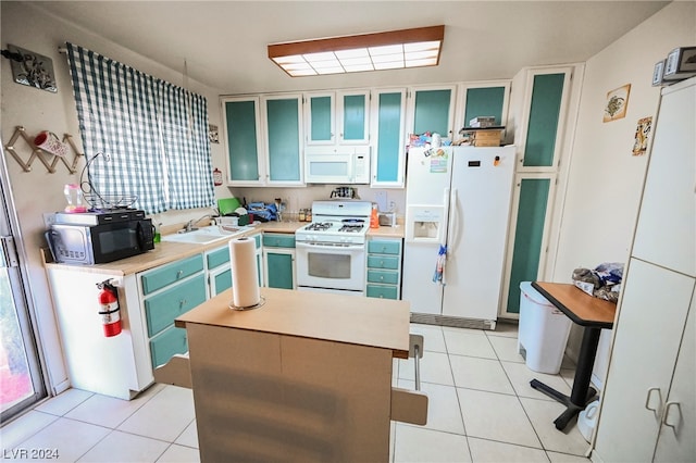 kitchen featuring light tile floors, white appliances, and sink