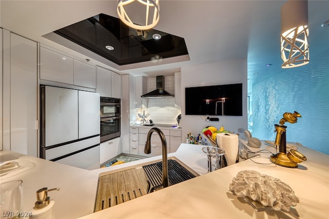 kitchen featuring high end white refrigerator, tasteful backsplash, wall chimney exhaust hood, white cabinetry, and stainless steel double oven