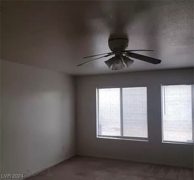 carpeted empty room with ceiling fan and plenty of natural light