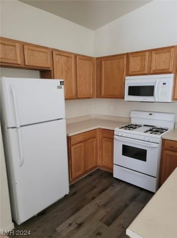 kitchen featuring white appliances and dark hardwood / wood-style floors