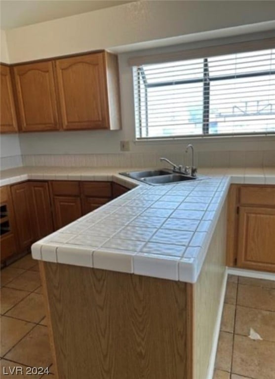 kitchen featuring tile counters, sink, and light tile floors