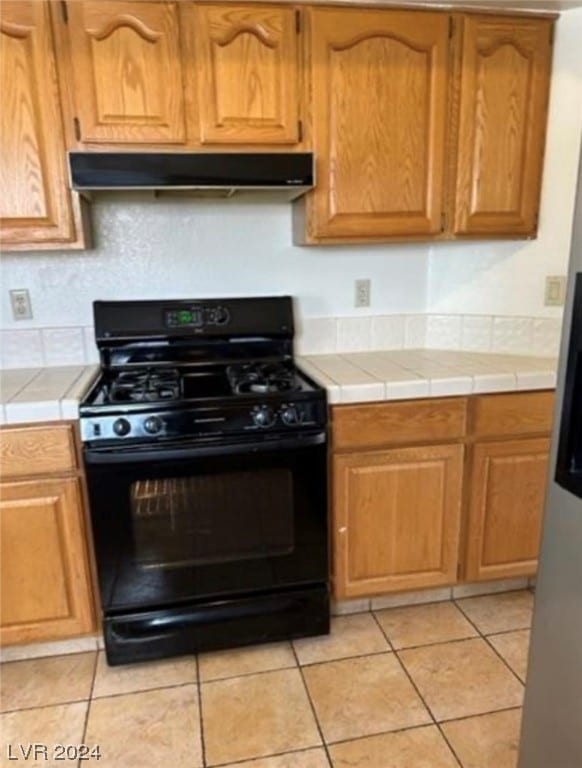 kitchen with light tile flooring, tile counters, and black range with gas stovetop