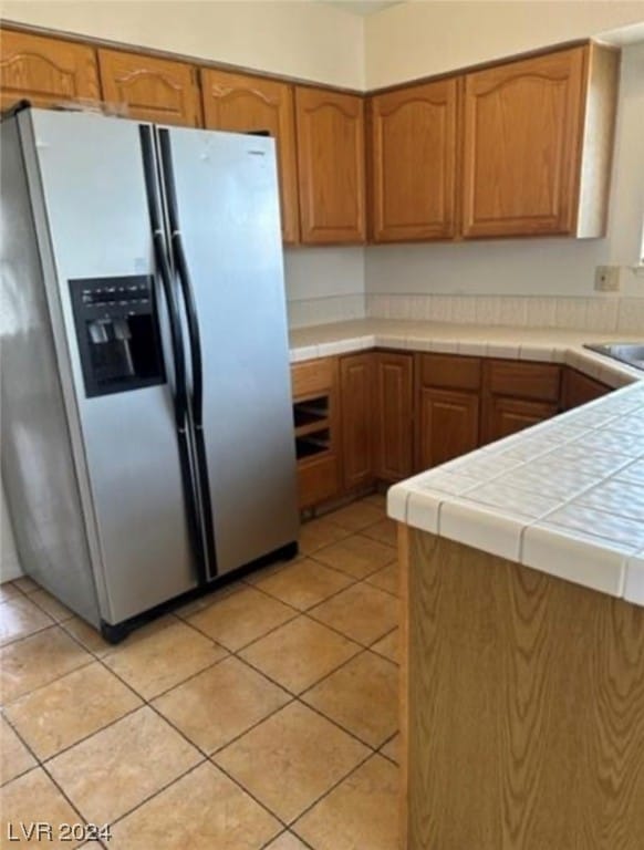 kitchen featuring tile countertops, stainless steel refrigerator with ice dispenser, and light tile flooring