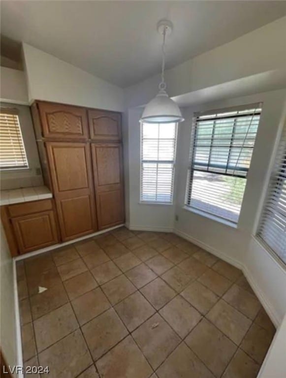 unfurnished dining area featuring light tile floors and vaulted ceiling