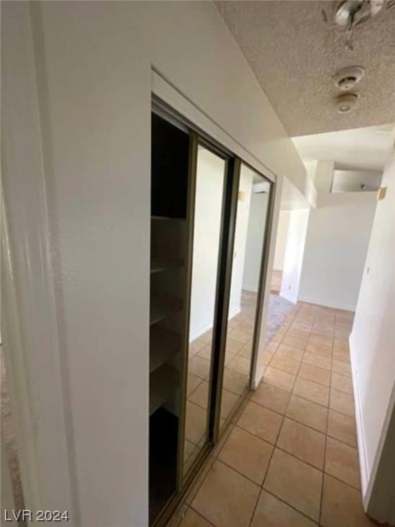 hallway with light tile flooring and a textured ceiling