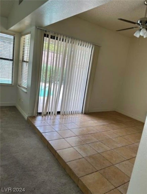 carpeted empty room with a textured ceiling and ceiling fan