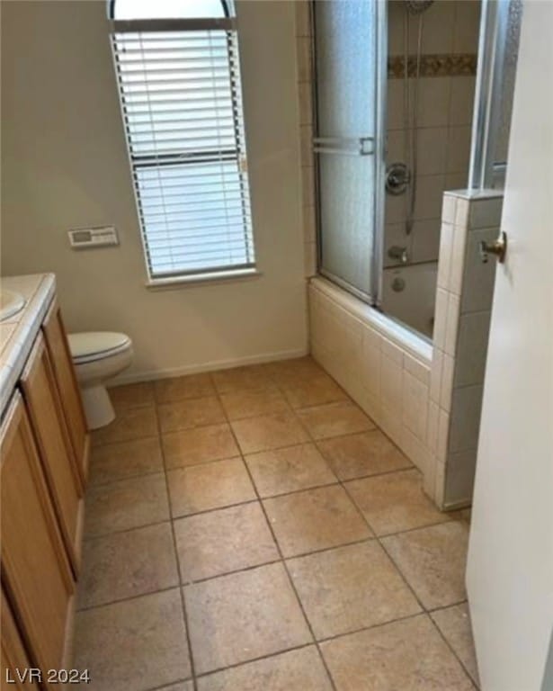 full bathroom with shower / bath combination with glass door, tile floors, toilet, and vanity