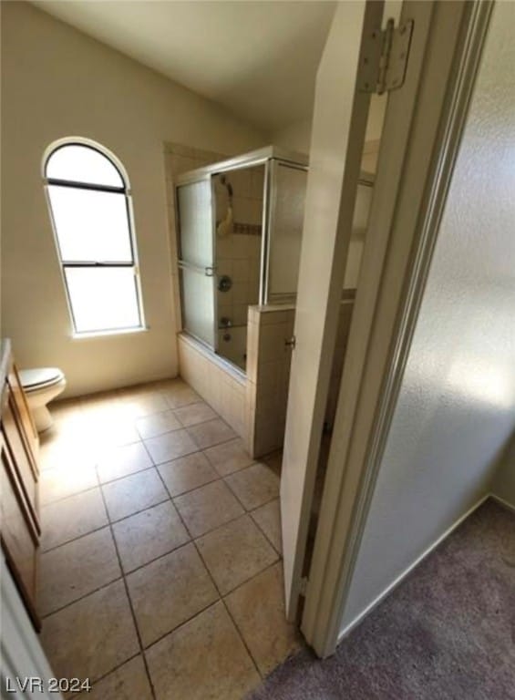 bathroom with walk in shower, toilet, and tile flooring