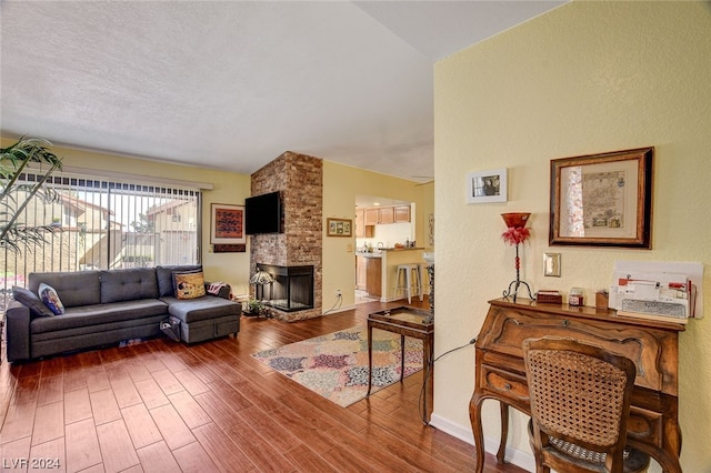 living room with a fireplace, a textured ceiling, high vaulted ceiling, and hardwood / wood-style floors