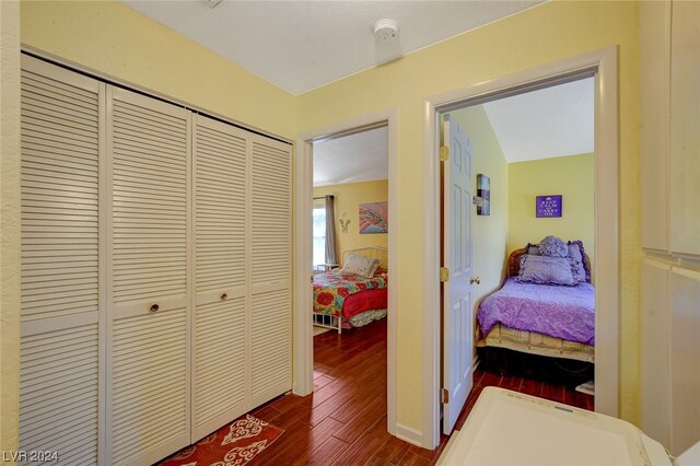 bedroom with a closet, dark wood-type flooring, and vaulted ceiling