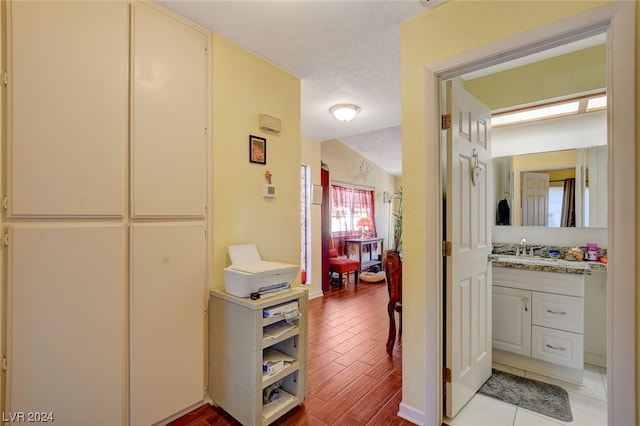 corridor featuring lofted ceiling, sink, and light wood-type flooring