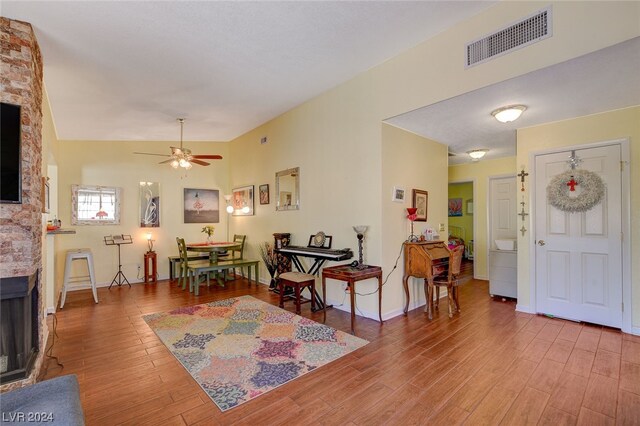 foyer entrance with a fireplace, lofted ceiling, light hardwood / wood-style floors, and ceiling fan