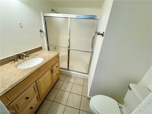 bathroom featuring toilet, tile flooring, a shower with shower door, and vanity