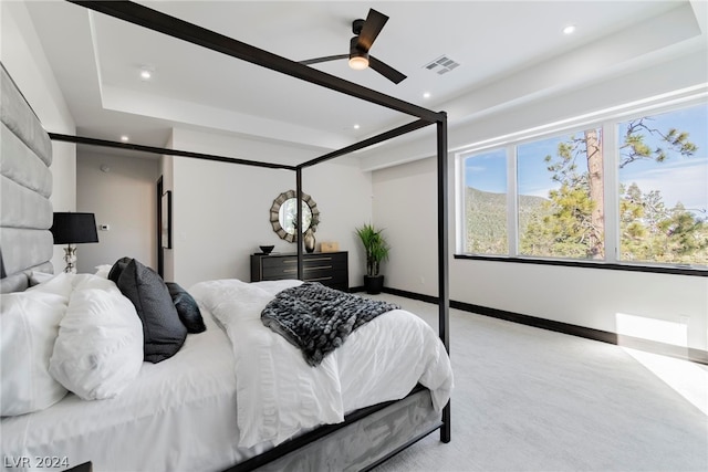 bedroom featuring ceiling fan, a raised ceiling, and light colored carpet