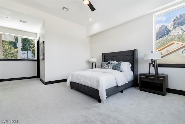 bedroom with multiple windows, ceiling fan, and light colored carpet