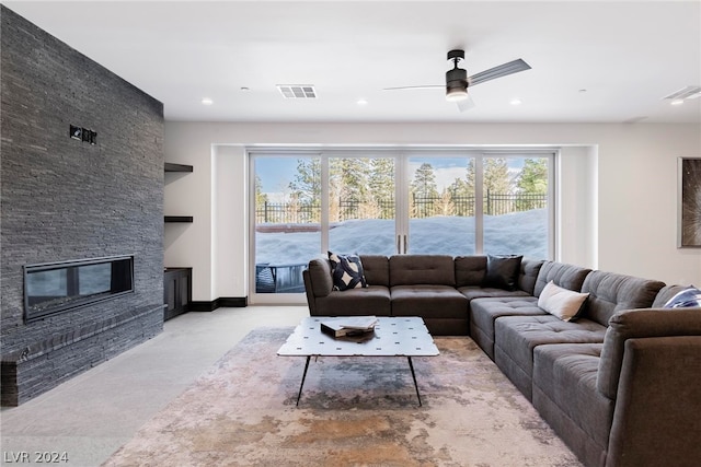 living room with ceiling fan and a stone fireplace