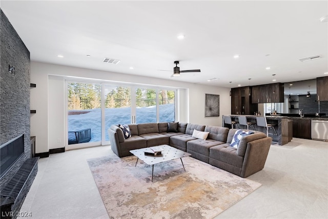 living room featuring a stone fireplace and ceiling fan