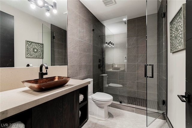 bathroom with tile flooring, toilet, vanity, and a shower with shower door