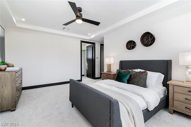 carpeted bedroom featuring ceiling fan and a raised ceiling