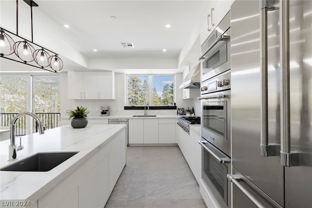 kitchen with white cabinets, light stone counters, and stainless steel appliances