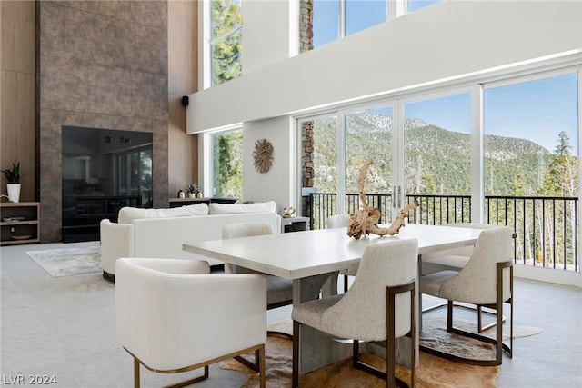 dining room featuring a mountain view, a tiled fireplace, light tile flooring, and a wealth of natural light