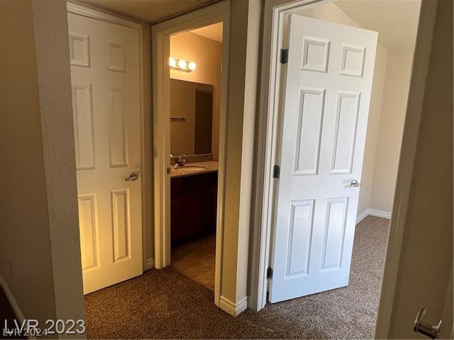 hall with sink and dark carpet