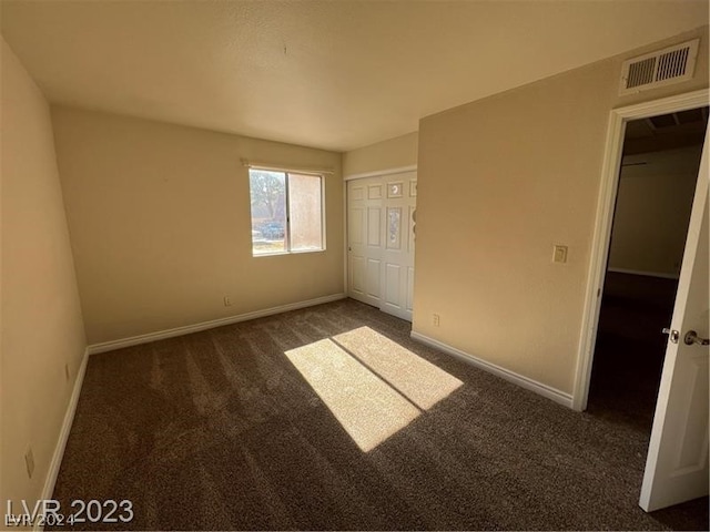 unfurnished bedroom with a closet and dark colored carpet