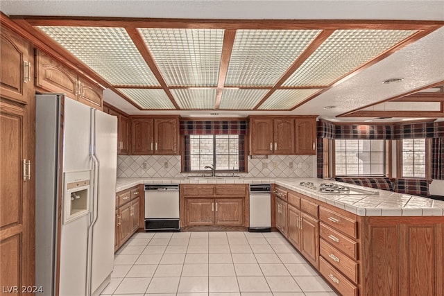 kitchen with white appliances, sink, backsplash, and light tile floors