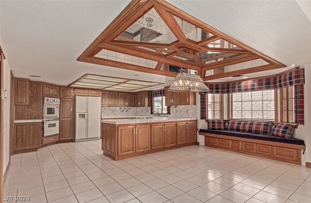 kitchen with white appliances, tile countertops, light tile flooring, and tasteful backsplash