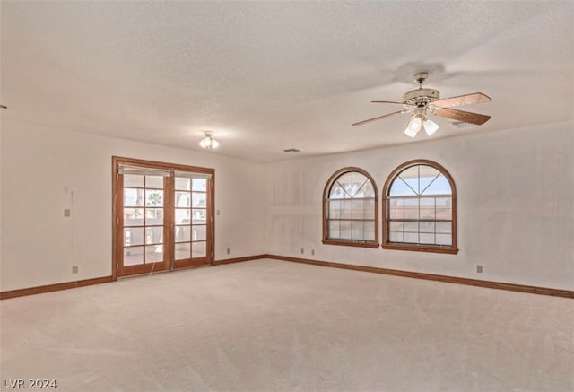 unfurnished room with french doors, a textured ceiling, light colored carpet, and ceiling fan