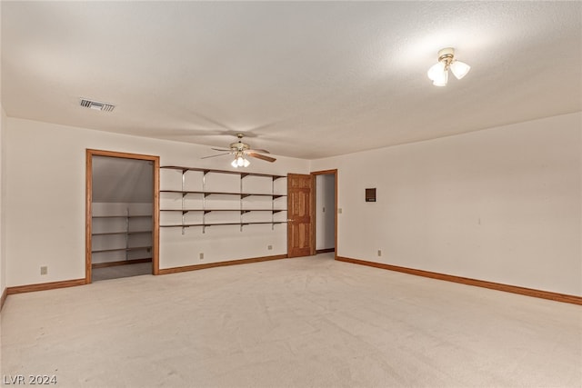 unfurnished bedroom with ceiling fan, a closet, light colored carpet, and a spacious closet