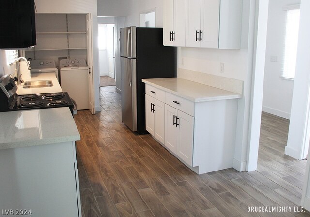 kitchen with washer and dryer, hardwood / wood-style flooring, electric range, and white cabinetry