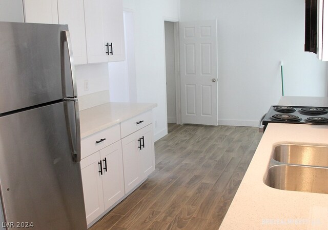 kitchen featuring stove, white cabinets, stainless steel fridge, and hardwood / wood-style flooring