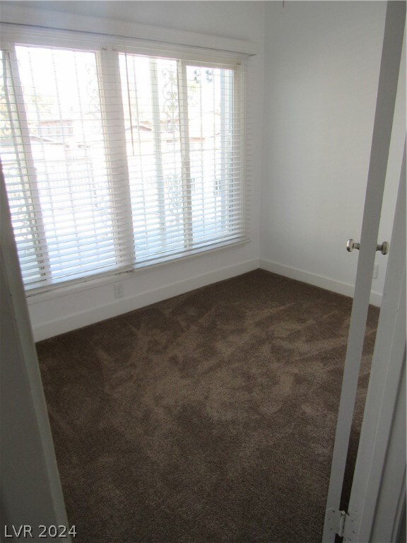 spare room featuring french doors and dark carpet