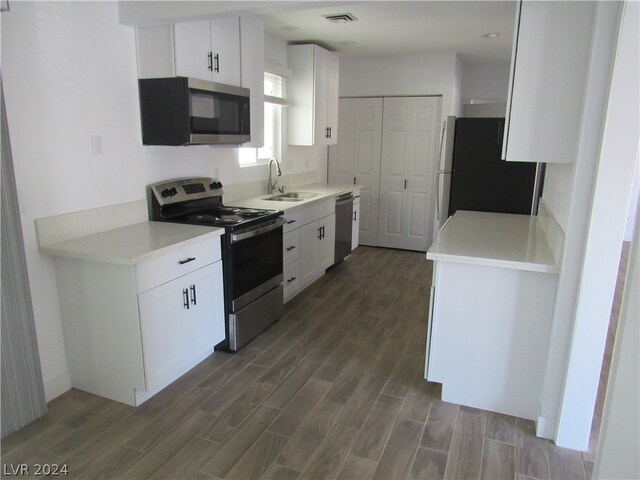 kitchen featuring sink, stainless steel appliances, dark wood-type flooring, and white cabinetry