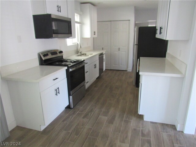 kitchen with appliances with stainless steel finishes, sink, dark hardwood / wood-style floors, and white cabinets