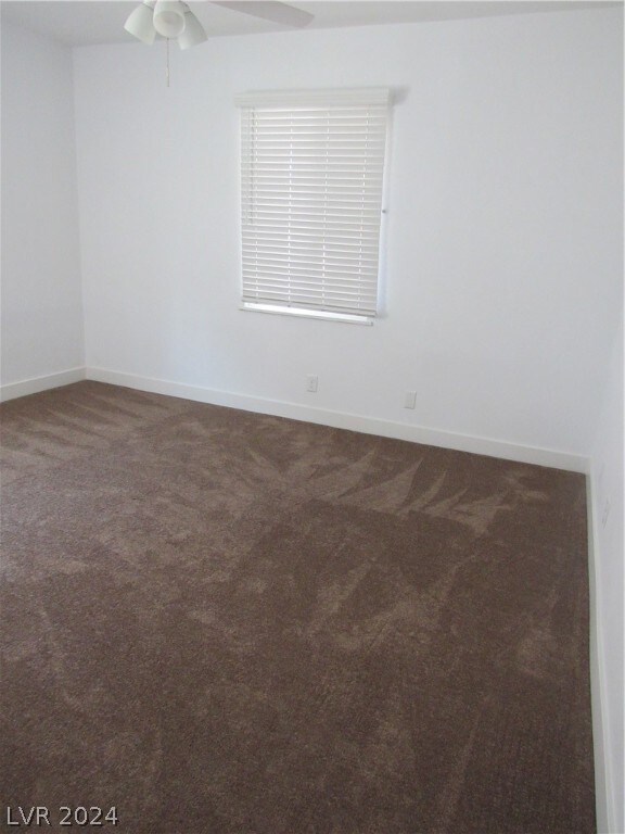 carpeted spare room featuring ceiling fan