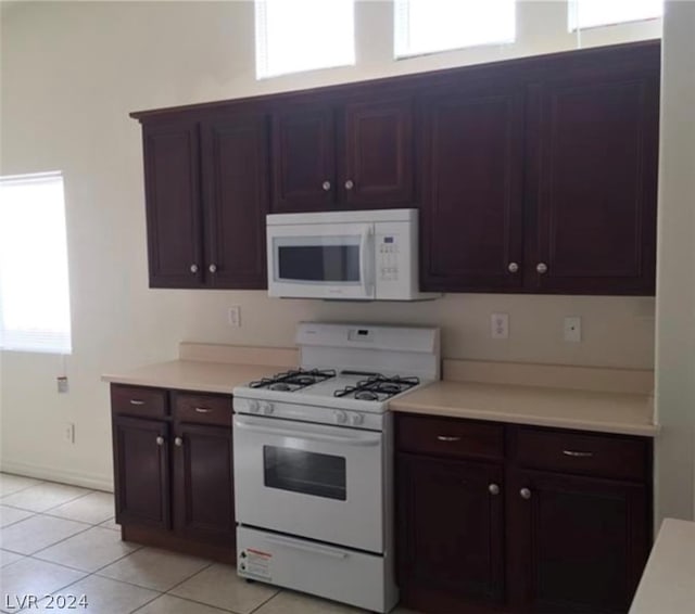 kitchen featuring white appliances, light tile floors, and dark brown cabinetry