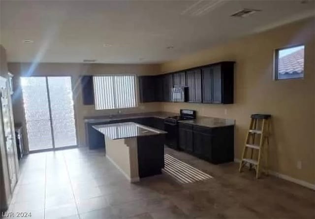 kitchen with black electric range oven, light tile floors, and a wealth of natural light