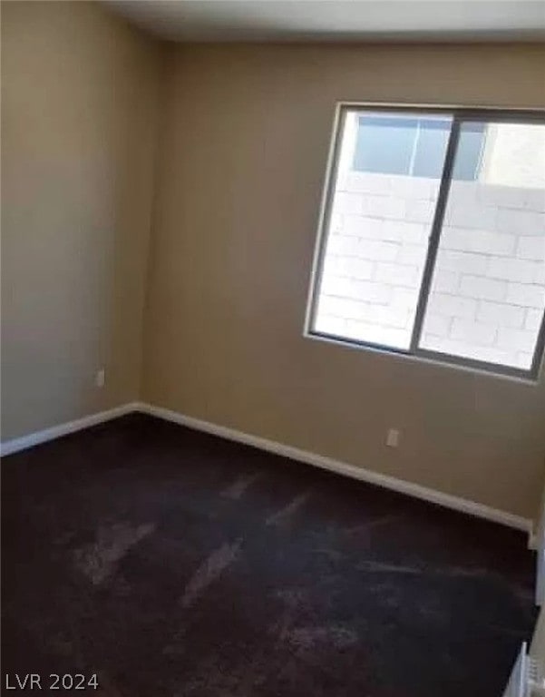 spare room featuring dark carpet and a healthy amount of sunlight