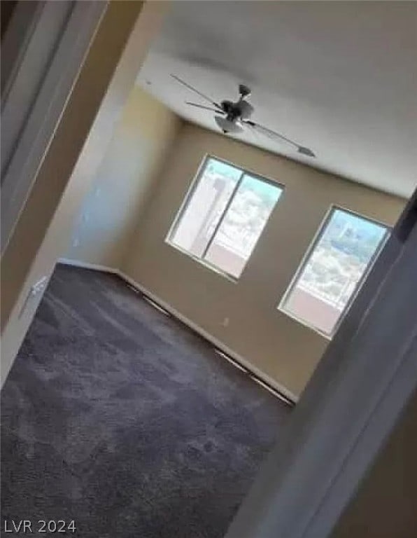 additional living space featuring ceiling fan and dark colored carpet